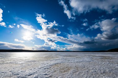Karla kaplı donmuş Kuito gölünün üzerindeki dramatik mavi gökyüzü, arka planda kozalaklı orman. Kış kır manzarası. Fırtına bulutları. Karelya Kuzey, Laponya
