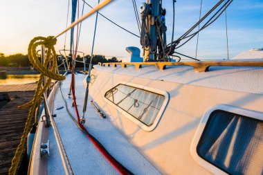 Beyaz yat gün batımında bir rıhtıma demirlemiş, yakın planda. Baltık Denizi, Ruhnu Adası, Estonya