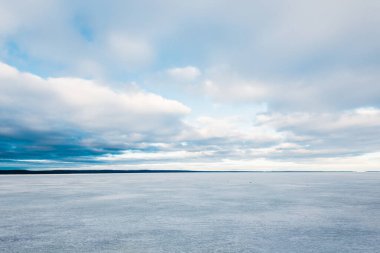 Kış manzarası. Gün batımında donmuş karla kaplı göl manzarası. Arka planda orman var. Renkli akşam bulutları. Onega Gölü, Karelia, Rusya