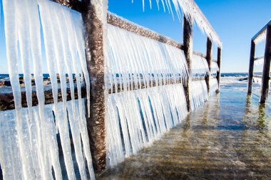 Güneşli bir günde, karla kaplı eski, paslı iskele. Buz parçaları yakın plan. Baltık Denizi, Letonya
