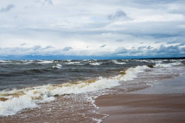 Dramatik gökyüzü ve dalgalar, deniz kıyısından bir manzara. Fırtınalı hava. Baltık Denizi, Letonya