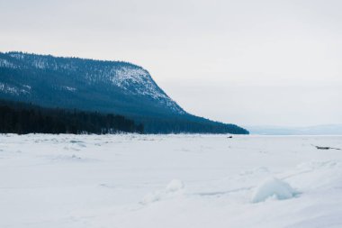 Kandalaksha körfezinin buz basıncıyla kaplı sırtı fırtınalı bir gökyüzünün altında. Renkli akşam bulutları. Arka planda Kola Yarımadası 'nın dağları ve kozalaklı ormanları var. Beyaz deniz, Kutup dairesi, Karelia, Rusya