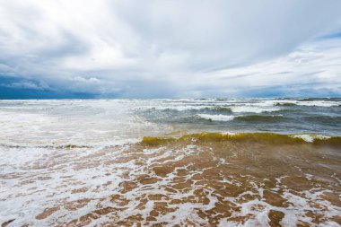 Dramatik gökyüzü ve dalgalar, deniz kıyısından bir manzara. Fırtınalı hava. Baltık Denizi, Letonya