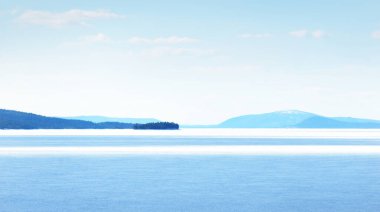 Donmuş gölün panoramik manzarası. Arka planda karla kaplı dağlar ve kozalaklı ormanlar var. Açık mavi gökyüzü. Kola Yarımadası, Murmansk bölgesi, Kutup Dairesi, Karelia, Rusya