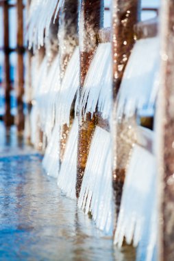 Güneşli bir günde, karla kaplı eski, paslı iskele. Buz parçaları yakın plan. Baltık Denizi, Letonya