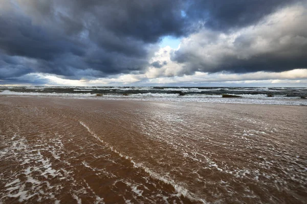 Autumn. Storm clouds above the sea. Waves and water splashes. Warm evening sunlight. Baltic sea, Garciems, Latvia