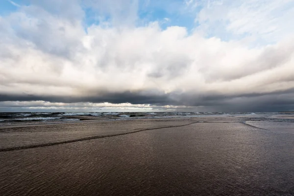 Autumn. Storm clouds above the sea. Waves and water splashes. Warm evening sunlight. Baltic sea, Garciems, Latvia