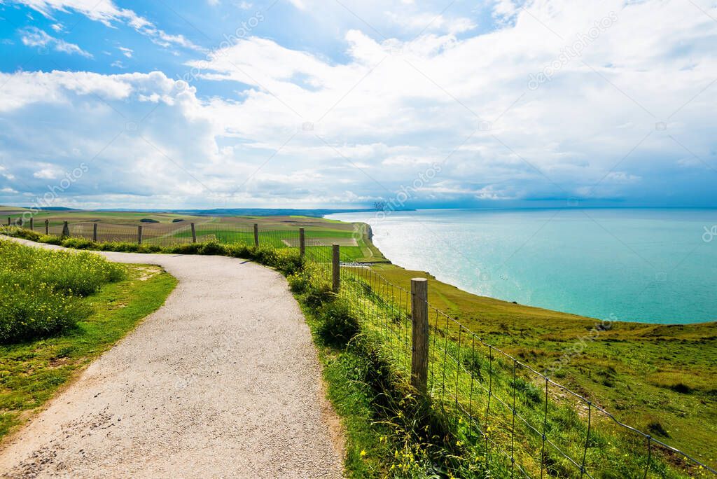 A country road through the valley near the cliffs of the English Channel. Green grass, azure water, clear blue sky. Idyllic summer scene. Cap Gris Nez, Pas-de-Calais, France