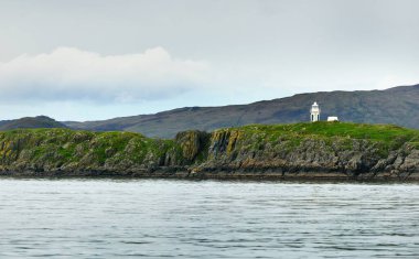 Islay adasının yeşil kıyılarının, vadilerinin ve tepelerinin panoramik manzarası. Küçük bir deniz feneri. Inner Hebrides, Argyll ve Bute, İskoçya, İngiltere