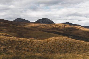Karanlık fırtına gökyüzünün altındaki Paps of Jura 'nın (Beinn an ir) en yüksek dağı yakınındaki vadinin panoramik manzarası. Dramatik bulutlar. Jura Adası, Inner Hebrides, İskoçya, İngiltere. Atmosferik manzara.