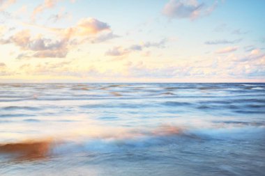 Gök gürültülü bir fırtınadan sonra denizin üstünde destansı pembe gün batımı bulutları. Dramatik bir gökyüzü. Dalgalar ve su dokuya sıçrar. Idyllic deniz manzarası. Kavramsal görüntü, uzun pozlama. Resim gibi bir manzara.