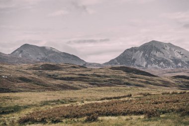 Karanlık fırtına gökyüzünün altındaki Paps of Jura 'nın (Beinn an ir) en yüksek dağı yakınındaki vadinin panoramik manzarası. Dramatik bulutlar. Jura Adası, Inner Hebrides, İskoçya, İngiltere. Atmosferik manzara.