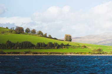 Clyde Nehri 'nin kayalık kıyısı, yelkenli tekneden panoramik manzara. Fırtınadan sonra dramatik bir gökyüzü. İskoçya, İngiltere. Seyahat yerleri, eko turizm, tatiller, saf doğa. Atmosferik manzara