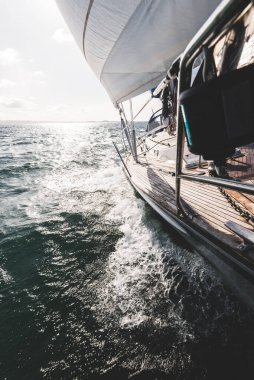 Dalgalarda yarışan ahşap meşe güverteli modern yatla donatılmış. Güverteden pruvaya bir manzara. Su, yakından sıçrıyor. Islay Adası, Inner Hebrides, İskoçya, İngiltere. Spor ve eğlence.