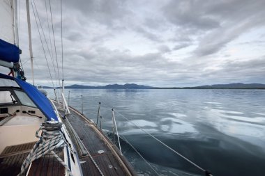 Tahta meşe güverteli bir yat bulutlu bir günde yelken açıyor güverteden güverteye bir manzara, direkler ve yelkenler. Inner Hebrides, İskoçya, İngiltere. Ulaşım, spor, yelkencilik, eğlence, seyahat