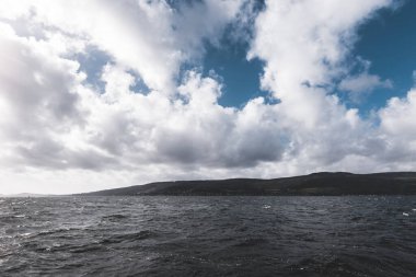 Clyde Nehri 'nin kayalık kıyısı, yelkenli tekneden panoramik manzara. Fırtınadan sonra dramatik bir gökyüzü. İskoçya, İngiltere. Seyahat yerleri, eko turizm, tatiller, saf doğa. Atmosferik manzara