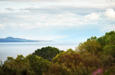 Küçük bir Ardrishaig köyünün kayalık kıyıları ve ormanlarının panoramik hava manzarası. Dramatik bulut manzarası. Loch Fyne, Crinan Kanalı, Argyll ve Bute, İskoçya, İngiltere