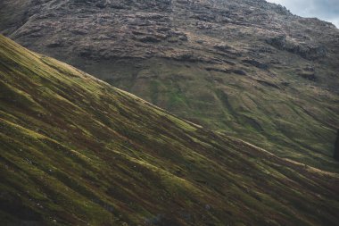 Yeşil kayalık kıyılar ve dramatik mavi gökyüzünün altındaki tepeler. Lomond Gölü ve Trossachs Ulusal Parkı, Inner Hebrides, İskoçya, İngiltere. Seyahat yerleri, eko turizm, yürüyüş, boş zaman aktiviteleri