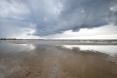 Gün batımında fırtınadan sonra Baltık Denizi kıyısında bir sürü koyu renkli kümülüs bulutu olan açık bir gökyüzü. Dramatik bulut manzarası. Resimli bir manzara var. Kararsız hava, mevsimler, iklim değişikliği