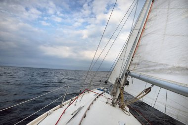 Beyaz yat yakın mesafede, güverteden pruvaya yakın görüntü, direk ve yelkenler. Kuzey denizi, Norveç. Dramatik bulut manzarası. Yelkencilik, yarış, spor, eğlence, eğlence etkinliği teması