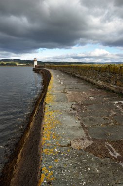 Eski deniz fenerine doğru boş bir gezinti, yakın plan. Arka planda kayalık kıyılar var. Dramatik mavi gökyüzü. Ardrishaig, İskoçya, İngiltere. Spor ve eğlence teması