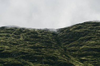 Yeşil kayalık kıyılar ve dramatik mavi gökyüzünün altındaki tepeler. Lomond Gölü ve Trossachs Ulusal Parkı, Inner Hebrides, İskoçya, İngiltere. Seyahat yerleri, eko turizm, yürüyüş, boş zaman aktiviteleri