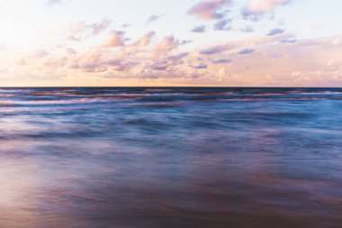 Gök gürültülü bir fırtınadan sonra denizin üstünde destansı pembe gün batımı bulutları. Dramatik bir gökyüzü. Dalgalar ve su dokuya sıçrar. Idyllic deniz manzarası. Kavramsal görüntü, uzun pozlama. Resim gibi bir manzara.