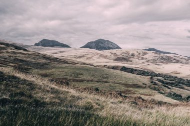 Karanlık fırtına gökyüzünün altındaki Paps of Jura 'nın (Beinn an ir) en yüksek dağı yakınındaki vadinin panoramik manzarası. Dramatik bulutlar. Jura Adası, Inner Hebrides, İskoçya, İngiltere. Atmosferik manzara.