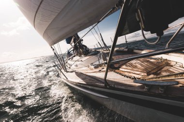 Dalgalarda yarışan ahşap meşe güverteli modern yatla donatılmış. Güverteden pruvaya bir manzara. Su, yakından sıçrıyor. Islay Adası, Inner Hebrides, İskoçya, İngiltere. Spor ve eğlence.