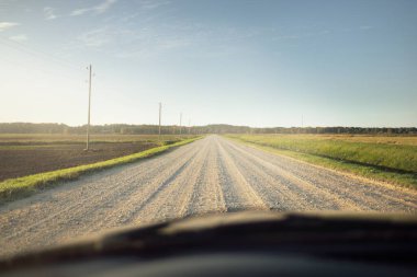 Gün batımında yeşil tarlalardan geçen boş bir köy yolu. Transformatör direkleri yakın çekim. Idyllic kırsal alanı, ABD. Seyahat yerleri, sürüş, özgürlük, turizm, gezi. Arabadan görüntüle
