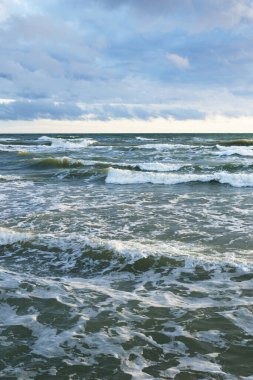 Gün batımında fırtınadan sonra Baltık Denizi. Letonya 'da sızıntı var. Renkli parlayan bulutlar. Dalgalar ve su sıçramaları. Destansı deniz manzarası. Kasırga, fırtına, dönek hava, meteoroloji, ekoloji