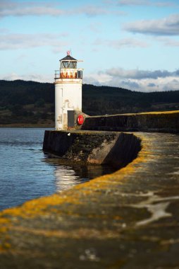 Eski deniz fenerine doğru boş bir gezinti, yakın plan. Arka planda kayalık kıyılar var. Dramatik mavi gökyüzü. Ardrishaig, İskoçya, İngiltere. Spor ve eğlence teması