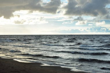 Gün batımında fırtınadan sonra Baltık kıyıları üzerinde parlayan kümülüs bulutlarıyla açık bir gökyüzü. Dramatik bulut manzarası. Resimli bir manzara var. Hava kararsız. Seyahat yeri, eko turizm konsepti