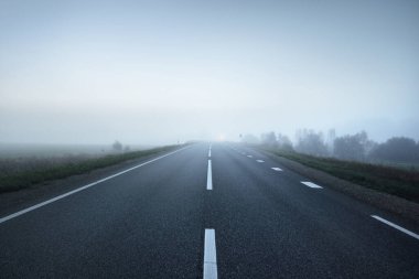 Gece sisli bir havada boş otobanın panoramik görüntüsü. Ay ışığı, temiz gökyüzü. Gün doğumu. Avrupa. Ulaşım, lojistik, seyahat, yolculuk, özgürlük, sürüş. Kırsal alan