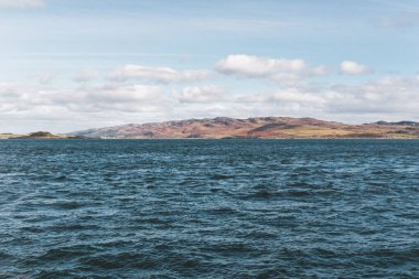 Yat manzaralı Jura adasının batı kıyısındaki kayalık kıyılara (uçurumlara) yelken açmak. Parlak bulutlu dramatik günbatımı gökyüzü. Inner Hebrides, İskoçya, İngiltere. Seyahat yerleri, işaretler