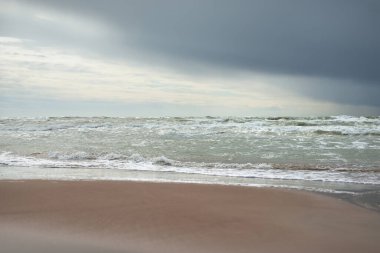 Fırtına sonrası dramatik bulutların altında Baltık Denizi 'nin kumlu sahili. Letonya 'da sızıntı var. Destansı deniz manzarası. Kasırga, fırtına, sert hava, meteoroloji, iklim değişikliği, doğal fenomen