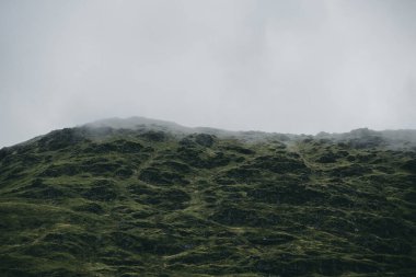 Yeşil kayalık kıyılar ve tepeler akşam sisi bulutları içinde. Lomond Gölü ve Trossachs Ulusal Parkı, Inner Hebrides, İskoçya, İngiltere. Seyahat yerleri, eko turizm, yürüyüş, boş zaman aktiviteleri