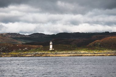 Dramatik gökyüzü altında Tarbert 'in kayalık kıyılarının panoramik manzarası. Arka planda deniz feneri, İskoçya, İngiltere. Seyahat yerleri, ulusal dönüm noktası, eğlence, eko turizm, tatiller