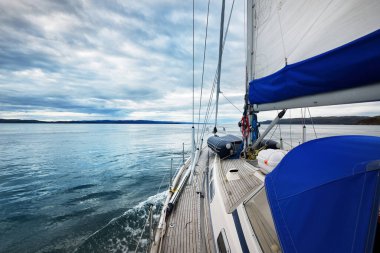 Tahta meşe güverteli bir yat bulutlu bir günde yelken açıyor güverteden güverteye bir manzara, direkler ve yelkenler. Inner Hebrides, İskoçya, İngiltere. Ulaşım, spor, yelkencilik, eğlence, seyahat