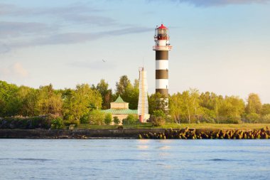 Eski bir deniz feneri, gün batımında menzil işareti ve dalgalar. Baltık Denizi, Riga, Letonya. Idyllic manzara. Yelkenlinin manzarası. Ulaşım, yelken, yön bulma. Umut ve barışın sembolü
