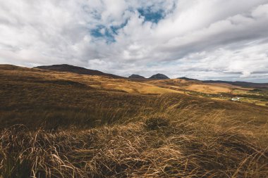 Karanlık fırtına gökyüzünün altındaki Paps of Jura 'nın (Beinn an ir) en yüksek dağı yakınındaki vadinin panoramik manzarası. Dramatik bulutlar. Jura Adası, Inner Hebrides, İskoçya, İngiltere. Atmosferik manzara.