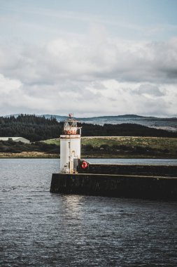 Eski deniz fenerine doğru boş bir gezinti, yakın plan. Arka planda kayalık kıyılar var. Dramatik bulut manzarası. Ardrishaig, Crinan Kanalı, İskoçya, İngiltere. Seyahat yerleri, gezi teması