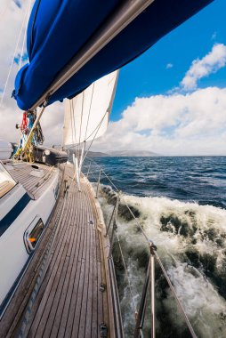 Teknelerle donatılmış modern bir yat. Tahta meşe güverteli. Clyde Nehri Firth 'ün kayalık kıyılarına doğru yol alıyorlar. Dramatik bir gökyüzü. İskoçya, İngiltere. Seyahat yerleri, eko turizm, tatiller, saf doğa.