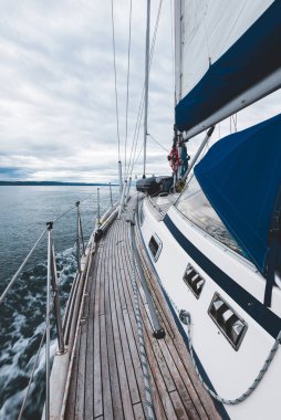 Bulutlu bir günde, Jura adasının kayalık kıyılarında seyir halindeki ahşap meşe güvertesiyle donatılmış modern bir yat. Inner Hebrides, İskoçya, İngiltere. Spor, eğlence, gezi, seyahat yerleri.