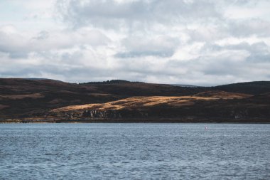 Dramatik gökyüzü altında Tarbert 'in kayalık kıyılarının panoramik manzarası. İskoçya, İngiltere. Seyahat yerleri, ulusal dönüm noktası, eğlence, eko turizm, tatiller, macera, keşif