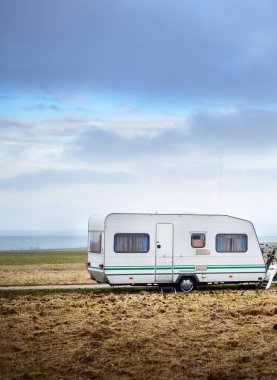 Gün batımında yeşil vadilerin arasına park etmiş bir karavan. Ulaşım, karavan, karavan, kamp, eko turizm, eğlence, alternatif yaşam tarzı. Tecrit, karantina, trafik yok.;
