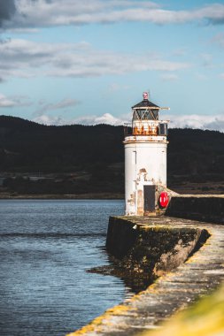 Eski deniz fenerine doğru boş bir gezinti, yakın plan. Arka planda kayalık kıyılar var. Dramatik bulut manzarası. Ardrishaig, Crinan Kanalı, İskoçya, İngiltere. Seyahat yerleri, gezi teması