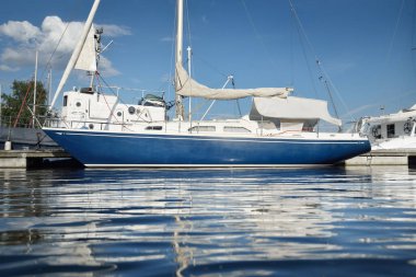 Klasik mavi şalvar donanımlı yat, marinada güneşli kapaklı demirli. Seyahat hayatı, tatil, yelkenli yolculuğu, yelkencilik, eğlence, eğlence aktivitesi, spor, ulaşım, su yüzeyi dokusu