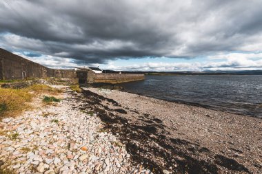 Eski deniz fenerine boş bir gezinti alanı, çakıllı plaj yakınlaşması. Dramatik bulut manzarası. Ardrishaig, Crinan Kanalı, İskoçya, İngiltere. Seyahat yerleri, gezi teması