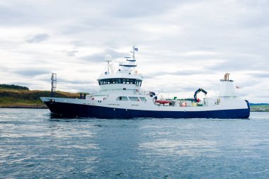 Jura adasının batı kıyısındaki kayalık kıyılarda yelken açan küçük bir gemi, yattan bir manzara. Fırtınadan sonra dramatik bulutlar. Inner Hebrides, İskoçya, İngiltere. Atmosferik manzara